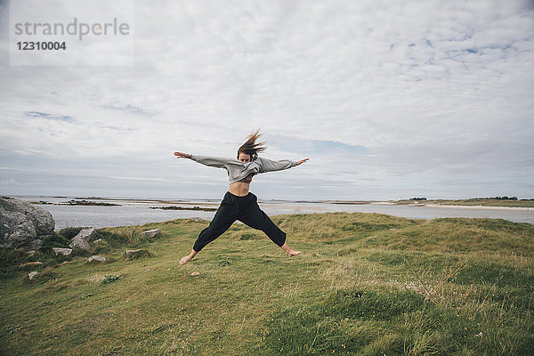 Frankreich  Bretagne  Landeda  Dunes de Sainte-Marguerite  junge Frau beim Springen an der Küste