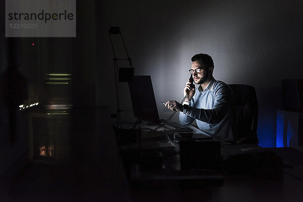 Geschäftsmann am Telefon im Büro bei Nacht