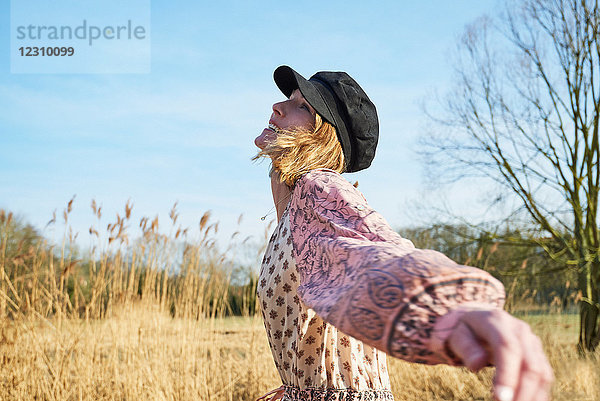 Frau im Hippie-Stil tanzt zwischen Schilf