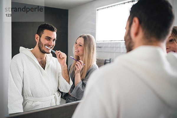 Spiegelbild eines Paares beim Zähneputzen im Badezimmer