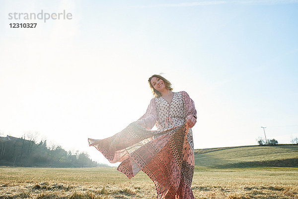 Frau im Hippiestil tanzt im Sonnenlicht im Feld  Porträt