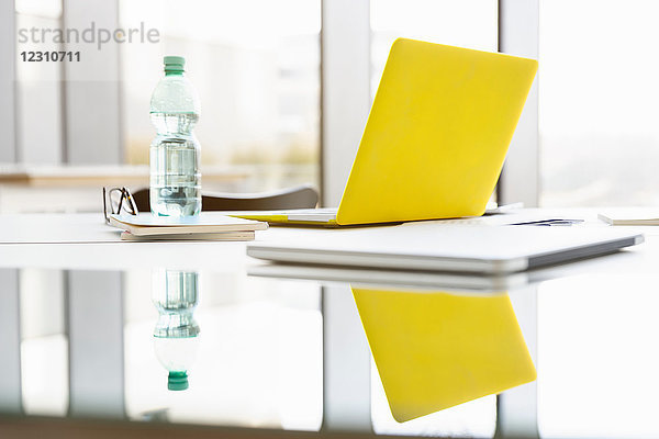 Gelber Laptop und Wasser in Flaschen im Sitzungssaal