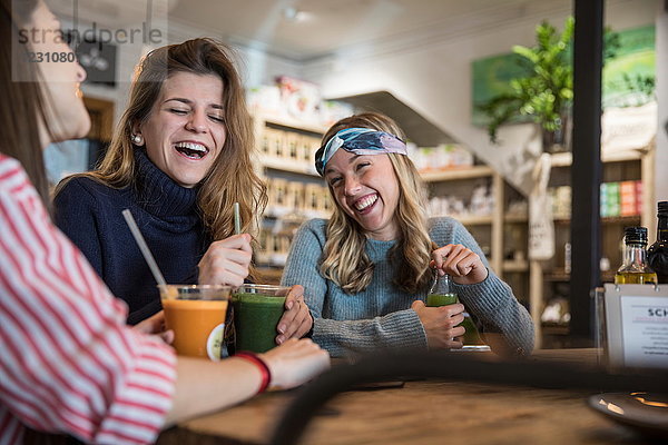 Drei Freundinnen  sitzen im Café  trinken Smoothies  lachen