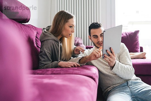Paar entspannt sich auf dem Sofa mit einem digitalen Tablett
