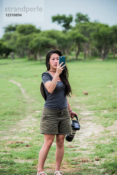 Junge Touristin fotografiert mit Smartphone und Kamera  Botswana  Afrika