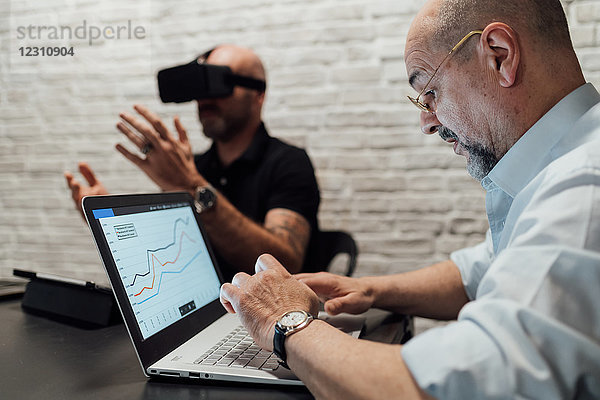 Mann benutzt Laptop und testet Virtual-Reality-Headset