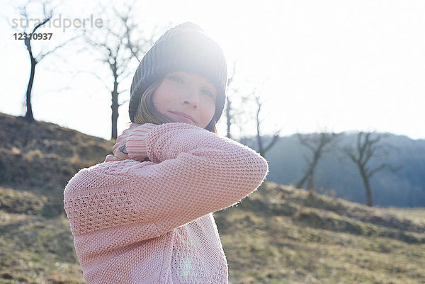 Sonnenlichtporträt einer mittleren erwachsenen Frau mit Strickmütze im Feld