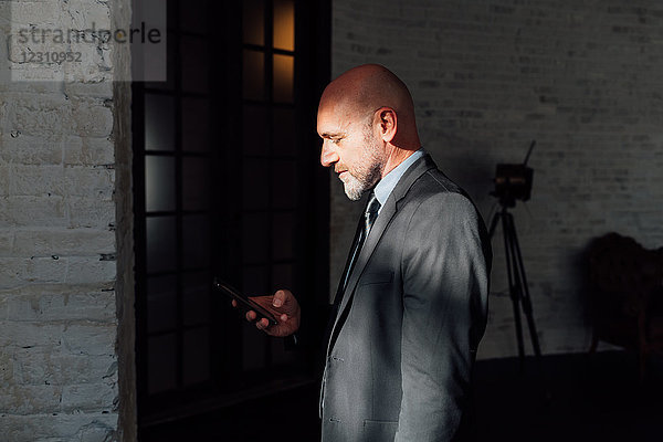 Porträt eines Geschäftsmannes mit Blick auf ein Smartphone