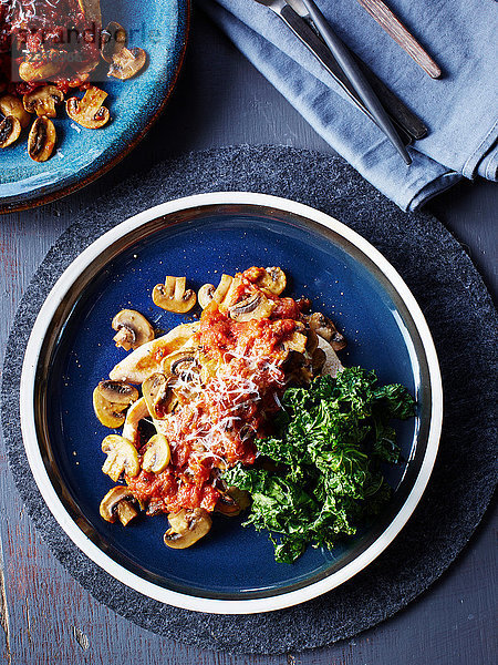 Stilleben mit Putenbrustteller  Pilzen  Parmesan und Grünkohlchips  Draufsicht