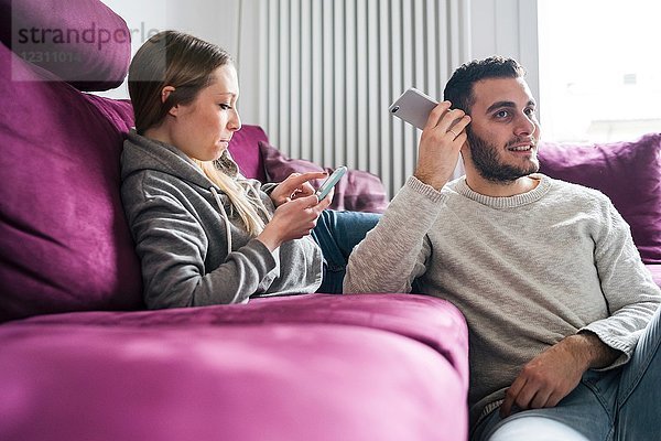 Paare entspannen sich auf dem Sofa mit Smartphones