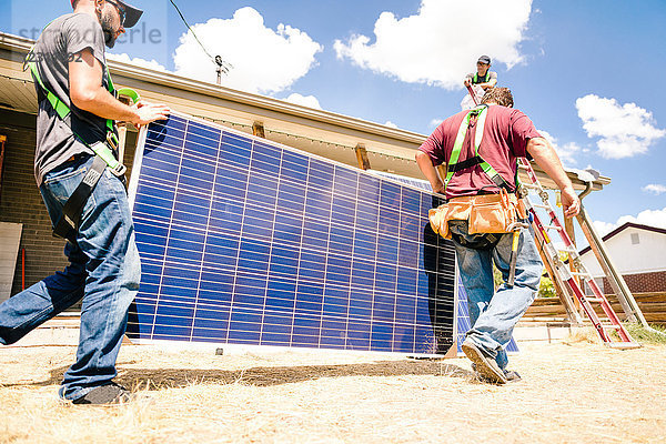 Handwerker  die Sonnenkollektoren tragen  Vorbereitung für die Installation  niedriger Blickwinkel