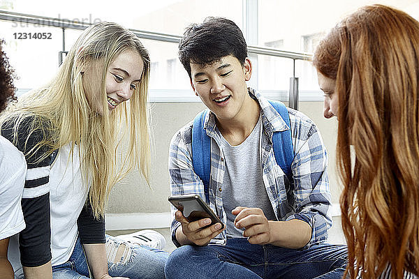 Schüler zeigt Mitschülern sein Smartphone