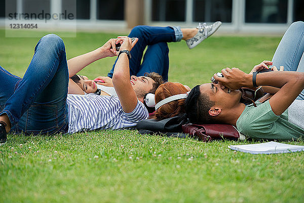 College-Studenten entspannen sich zwischen den Vorlesungen gemeinsam auf dem Rasen