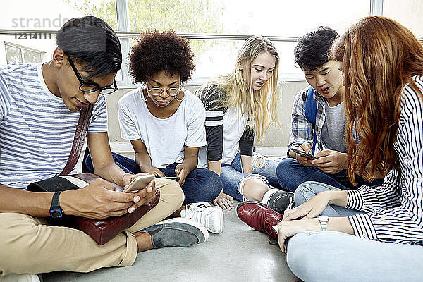 Schüler sitzen zusammen und benutzen Smartphones