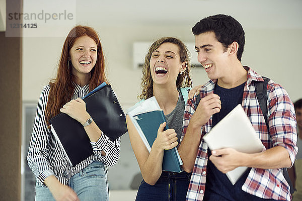 Klassenkameraden lachen zusammen beim Gehen im Schulkorridor
