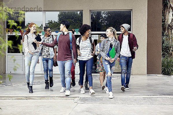 Klassenkameraden  die auf dem College-Campus spazieren gehen und miteinander plaudern