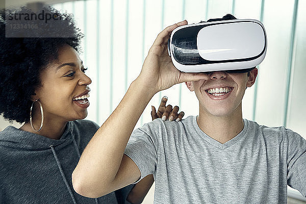 Junger Mann benutzt mit einem Freund einen Virtual-Reality-Simulator