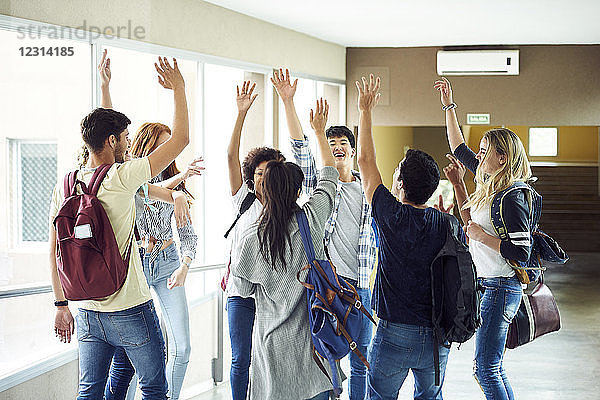 Gruppe von Schülern  die mit erhobenen Händen in einem Kreis im Korridor stehen
