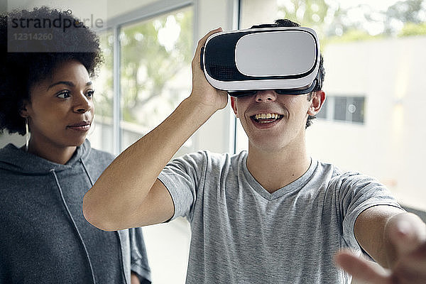 Junger Mann benutzt mit einem Freund einen Virtual-Reality-Simulator