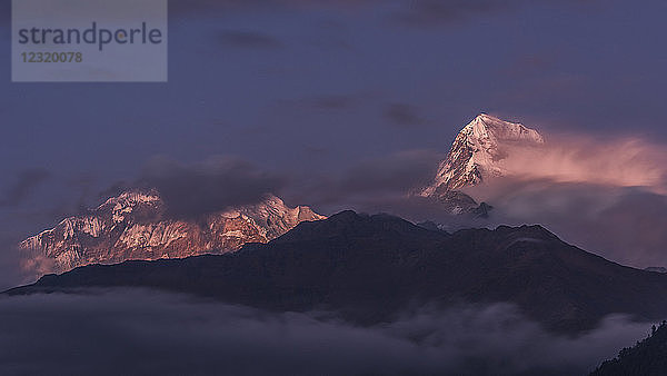 Die Wolken lichten sich allmählich und geben das Abendlicht auf Annapurna South frei  vom Poon Hill aus gesehen  Himalaya  Nepal  Asien