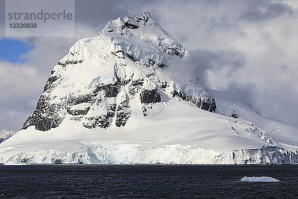 Gletscher  pyramidenförmige Bergspitze und dramatische Wolken und Himmel  Kap Errera  Wiencke Island  Antarktische Halbinsel  Antarktis  Polarregionen