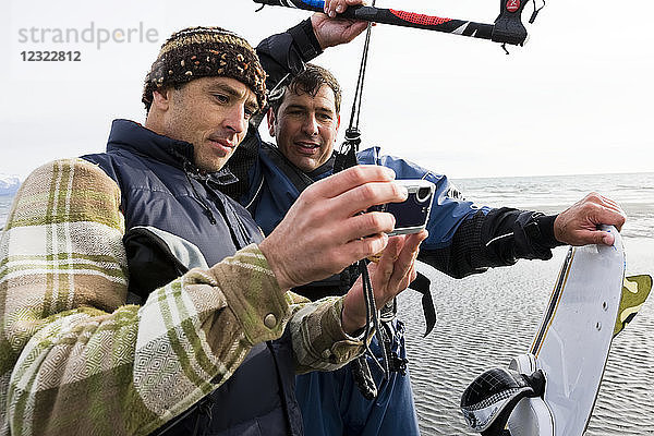 Zwei Männer prüfen Fotos auf einer Kamera während eines Kitesurfing-Kurses  Kachemak Bay  Süd-Zentral-Alaska; Alaska  Vereinigte Staaten von Amerika