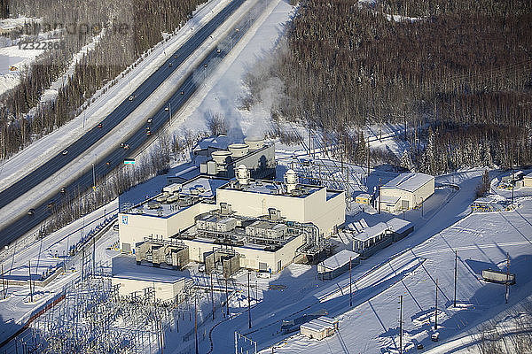 Luftaufnahme von Schnee  der das Gelände des städtischen Licht- und Kraftwerks am Glenn Highway bedeckt  Dampf  der aus den großen Schornsteinen auf dem Gebäude aufsteigt  Süd-Zentral-Alaska im Winter; Anchorage  Alaska  Vereinigte Staaten von Amerika