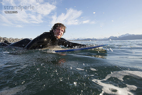 Surfer paddelt auf den Ozean hinaus  Südost-Alaska; Yakutat  Alaska  Vereinigte Staaten von Amerika