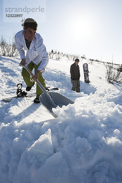 Snowboarder räumt Schnee mit einer Schaufel  Süd-Zentral-Alaska  Homer  Alaska  Vereinigte Staaten von Amerika