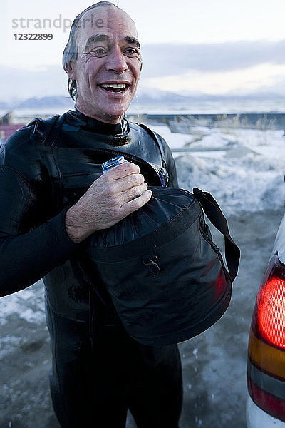 Mann beim Abspülen nach dem Surfen in der Kachemak Bay  Süd-Zentral-Alaska; Homer  Alaska  Vereinigte Staaten von Amerika