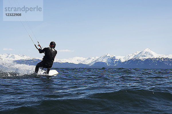 Mann beim Kitesurfen mit Kenai Mountains im Hintergrund  Süd-Zentral-Alaska; Homer  Alaska  Vereinigte Staaten von Amerika