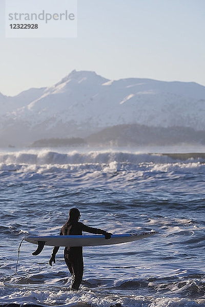 Surferin betritt das Wasser der Kachemak Bay  Süd-Zentral-Alaska; Homer  Alaska  Vereinigte Staaten von Amerika