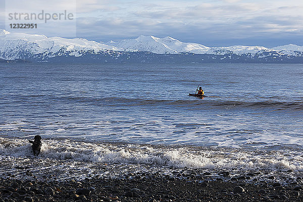 Seekajakfahren in der Kachemak Bay mit einem Hund  der im Wasser entlang des Ufers läuft  Süd-Zentral-Alaska; Homer  Alaska  Vereinigte Staaten von Amerika