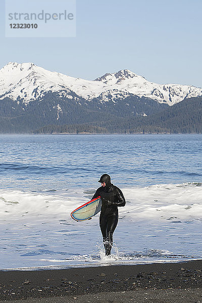 Surfer  der im Wasser an der Außenküste der Kenai-Halbinsel spazieren geht  Süd-Zentral-Alaska; Alaska  Vereinigte Staaten von Amerika