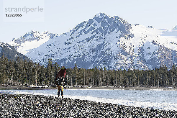 Mann  der mit einem Kajak spazieren geht  Kenai Peninsula Outer Coast  Süd-Zentral-Alaska; Alaska  Vereinigte Staaten von Amerika