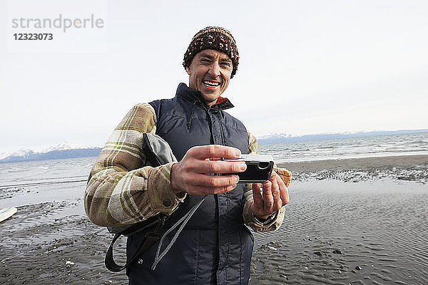 Mann am Strand von Homer mit einer Digitalkamera  Süd-Zentral-Alaska; Alaska  Vereinigte Staaten von Amerika