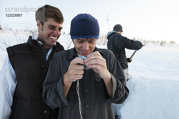 Snowboarder beim Betrachten von Bildern auf einer Digitalkamera  Süd-Zentral-Alaska; Homer  Alaska  Vereinigte Staaten von Amerika
