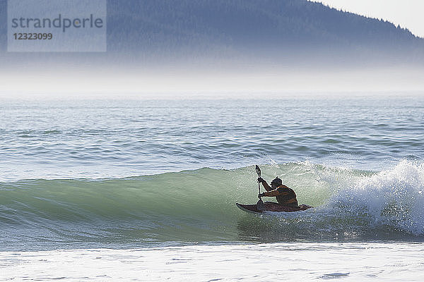 Person beim Kajakfahren und Surfen entlang der Außenküste der Kenai-Halbinsel  Süd-Zentral-Alaska; Alaska  Vereinigte Staaten von Amerika