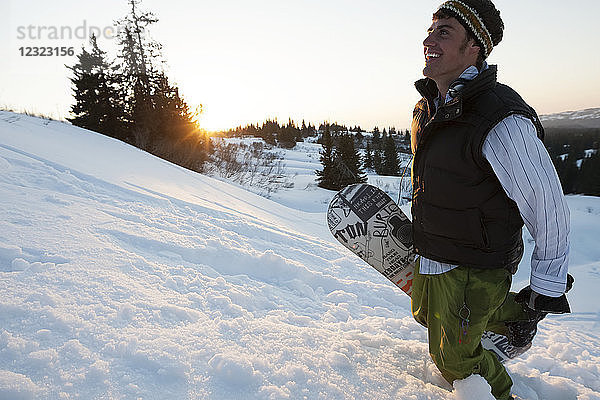 Snowboarder mit Snowboard auf einer verschneiten Piste bei Sonnenuntergang  Süd-Zentral-Alaska; Homer  Alaska  Vereinigte Staaten von Amerika