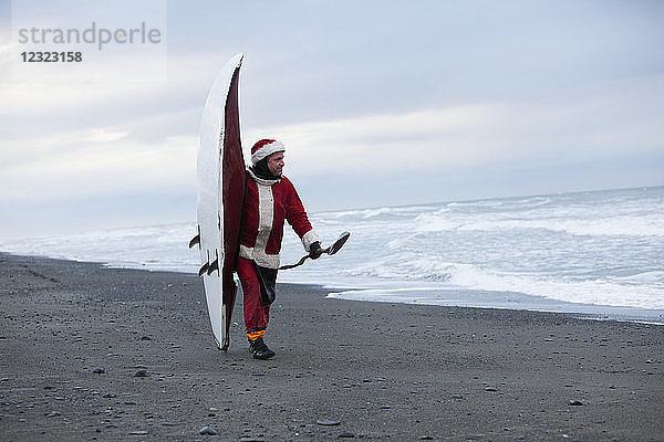 Mann im Weihnachtsmannkostüm mit Kajak an der Küste von Homer  Kenai-Halbinsel  Süd-Zentral-Alaska; Homer  Alaska  Vereinigte Staaten von Amerika
