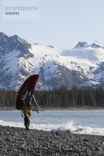 Surfer mit seinem Surfbrett entlang der Außenküste der Kenai-Halbinsel  Süd-Zentral-Alaska; Alaska  Vereinigte Staaten von Amerika
