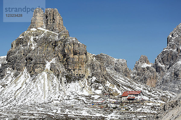 Berghotel auf einem schneebedeckten Felsgrat mit Bergen und blauem Himmel im Hintergrund; Sexten  Bozen  Italien