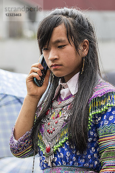 Hmong-Frau spricht auf dem Sonntagsmarkt mit einem Mobiltelefon; Bac Ha  Lao Cai  Vietnam