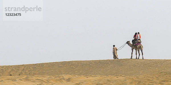 Ein Paar auf einer Kamelsafari in den Lakhmana-Dünen; Damodara  Rajasthan  Indien