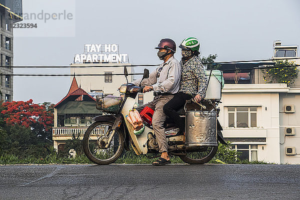 Pärchen auf einem mit Containern beladenen Motorrad in der Altstadt von Hanoi  Vietnam