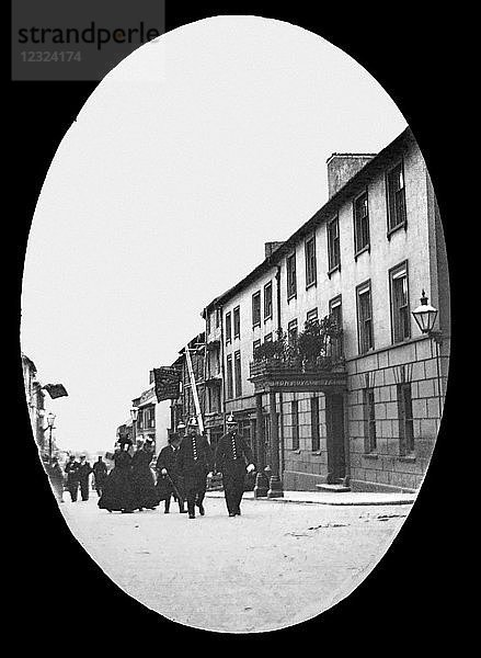 Laterna Magica um 1900  viktorianisch/edwardianisch  Sozialgeschichte. Zwei Polizisten  Damen und Herren  die auf der Straße am Lion Royal Hotel vorbeigeführt werden.