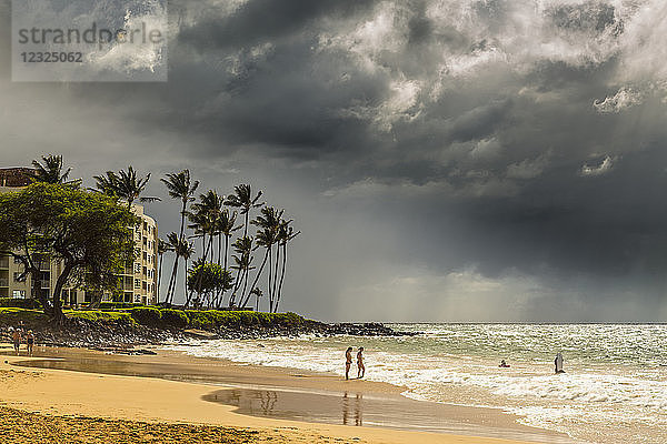 Touristen an einem Strand auf der Insel Maui mit dunklen Wolken und Regenfällen über dem Meer in der Ferne; Makawao  Maui  Hawaii  Vereinigte Staaten von Amerika