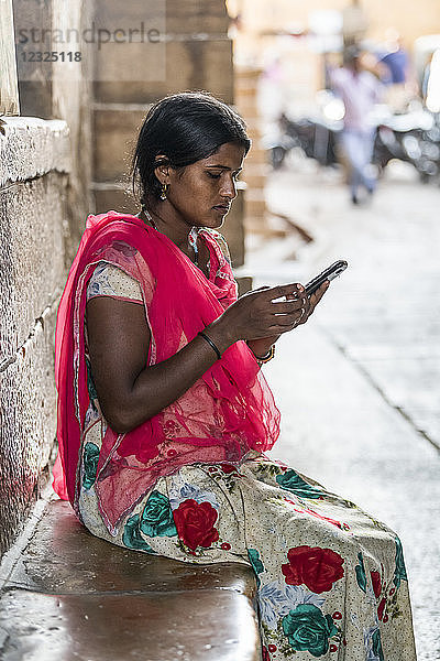 Eine junge indische Frau sitzt und benutzt ihr Mobiltelefon; Jaisalmer  Rajasthan  Indien