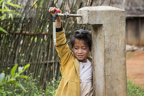 Hmong-Mädchen spielt mit einem Wasserhahn in Na Kam Peng  auch Bomb Village genannt  Xiangkhouang  Laos