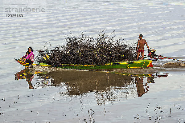 Mann und Frau mit einem Kind auf einem mit Holz beladenen Boot  das sich einem schwimmenden Dorf auf dem Tonle Sap nähert; Siem Reap  Kambodscha